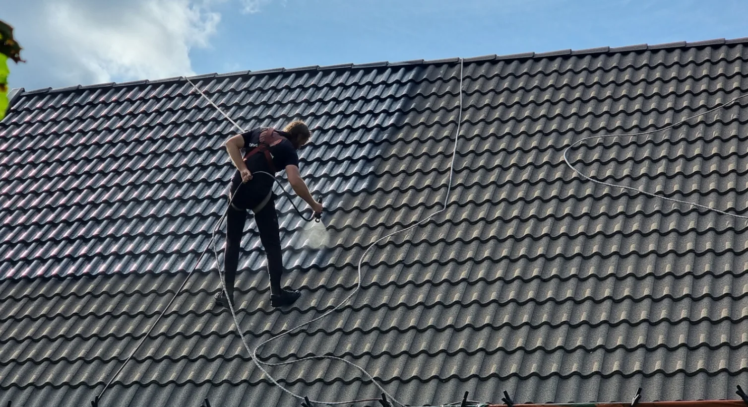 Roofer high-pressure washing and treating a roof in Ljungby